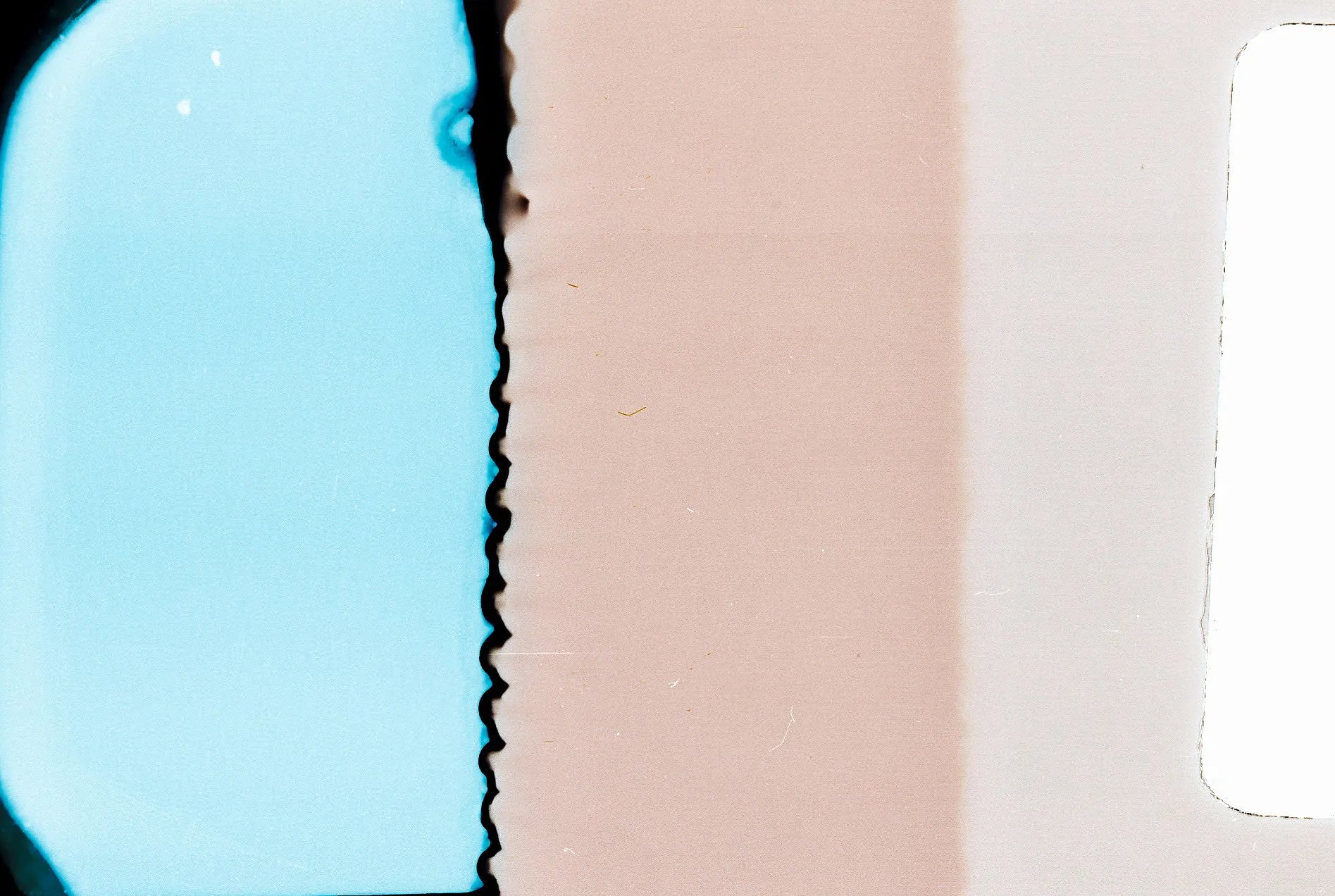 Abstract film scan: pale blue and pink bands split by a jagged black edge