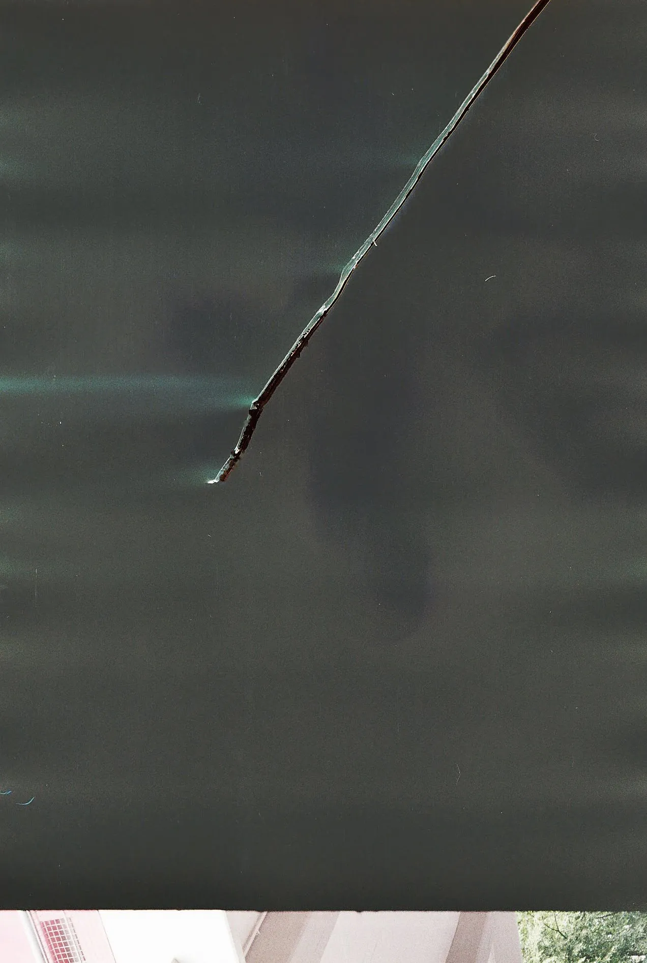 Abstract film scan: a thin wire crossing a dark green-grey field