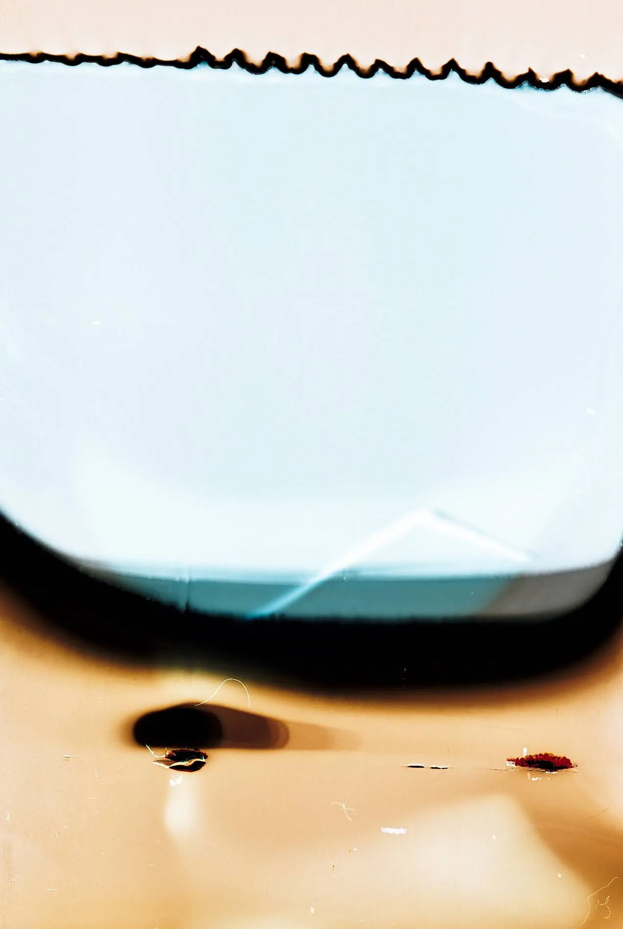 Abstract film scan: a pale blue shape with a jagged top edge over orange